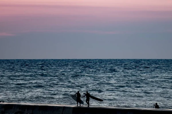 Силуэт людей с досками для серфинга у моря на закате — стоковое фото