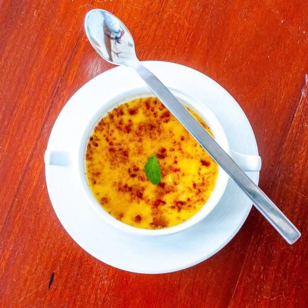 High angle shot of a delicious yellow dish with a spoon on a wooden surface — Stock Photo, Image