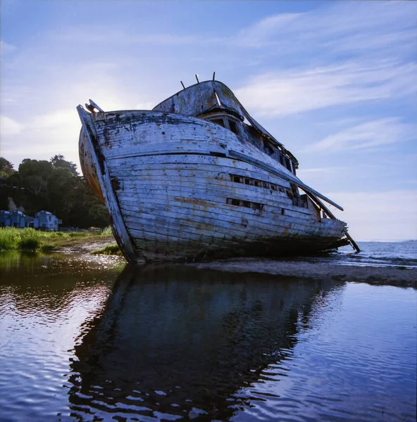 Flachbild eines alten, rostigen Schiffes, das sich im See unter dem wolkenverhangenen Himmel spiegelt — Stockfoto