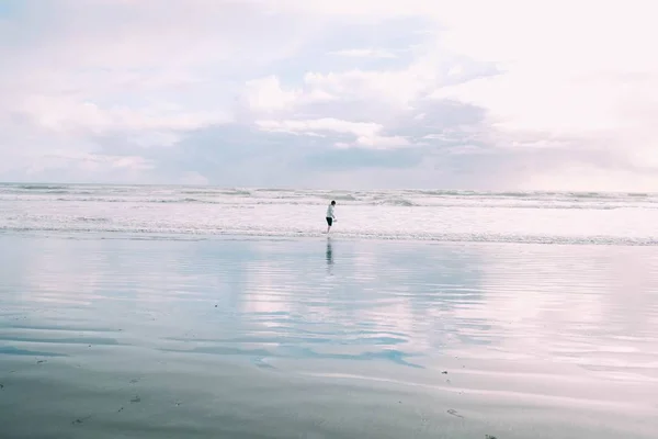 Young female walking along the seashore near the crazy sea waves during daytime — Stock Photo, Image