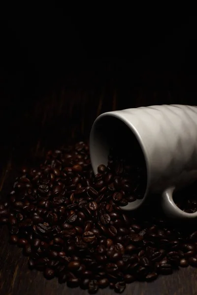 Pionowy Strzał Ziaren Kawy Rozlany Drewnianej Powierzchni Białej Filiżanki Kawy — Zdjęcie stockowe