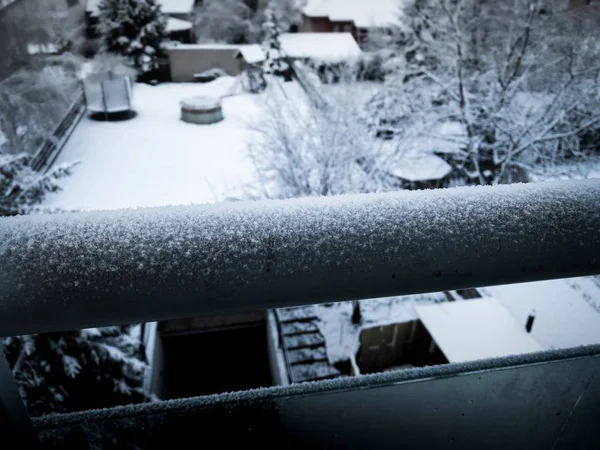 在雪天的阳台上，背景是树木丛生，操场被雪覆盖的景象 — 图库照片