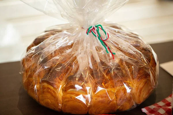 Closeup picture of sweet bread in a plastic bag on a wooden table with a blurry background — Stock Photo, Image