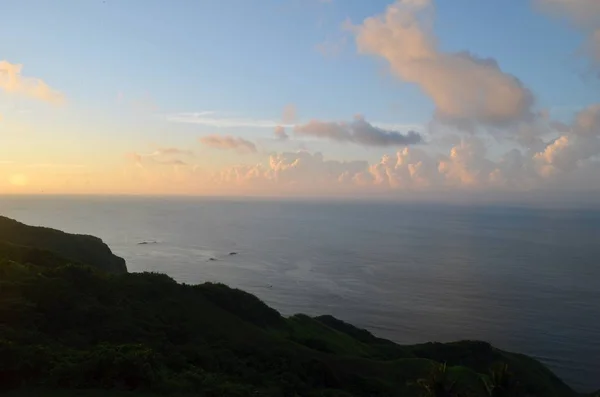 Ruhiges Meer umgeben von Hügeln und viel Grün bei Sonnenuntergang unter blauem Himmel — Stockfoto