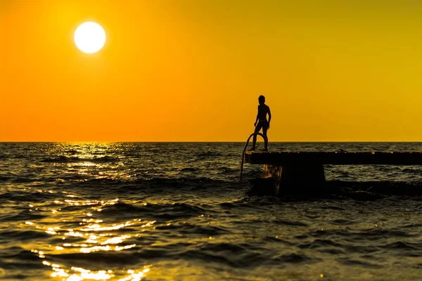 Σιλουέτα ενός ανθρώπου που ετοιμάζεται να πηδήξει στη θάλασσα με το όμορφο ηλιοβασίλεμα στο βάθος — Φωτογραφία Αρχείου