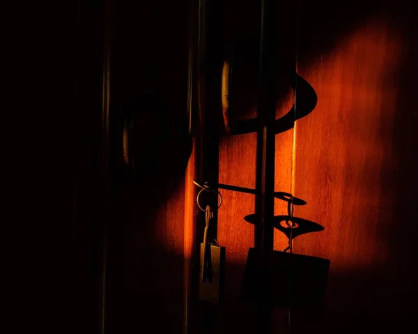 Avaimien lähikuva puisen oven kaapissa punaisten valojen ja varjojen alla — kuvapankkivalokuva