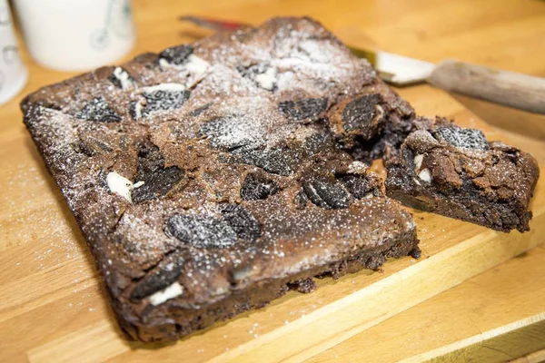 Aufnahme eines köstlichen Schokoladenkuchens mit Zucker und Keksgarnitur auf einer Holzoberfläche — Stockfoto