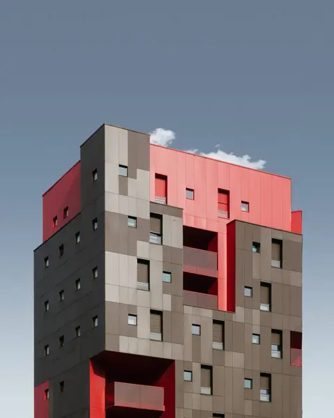 Függőleges alacsony szögű lövés egy piros és fekete modern épület a kék ég alatt — Stock Fotó