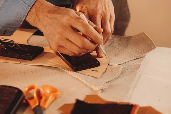 Lederwerker maakt een leren kleding met witte stof in een studio — Stockfoto