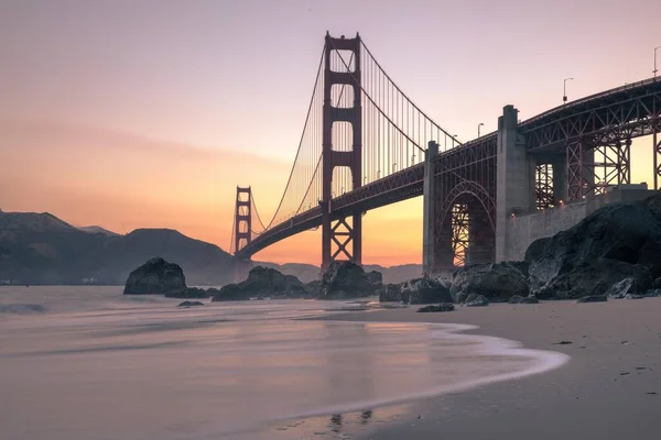 Ampla imagem da ponte Golden Gate perto do corpo de água durante o pôr do sol em São Francisco, Califórnia — Fotografia de Stock
