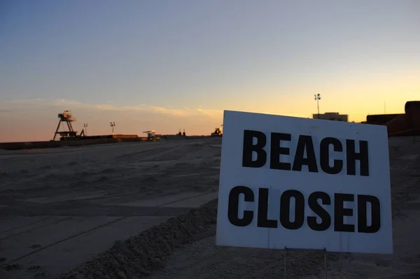 Белый пляж закрытый знак на пляже со строительной техникой на заднем плане — стоковое фото