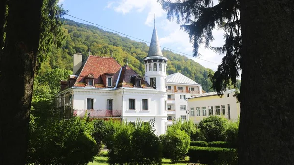 Manor house with white walls and a red roof in a garden surrounded by hills and forests in Romania — Stockfoto