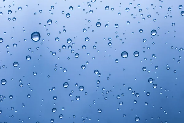 Veel waterdruppels van verschillende grootte op een blauwe achtergrond — Stockfoto