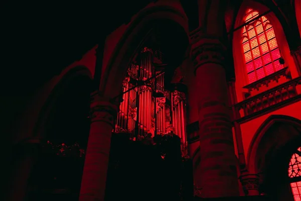 Χαμηλή γωνιακή άποψη εκκλησίας με τόξα και κίονες κάτω από κόκκινο νέον φως κατά τη διάρκεια της νύχτας — Φωτογραφία Αρχείου