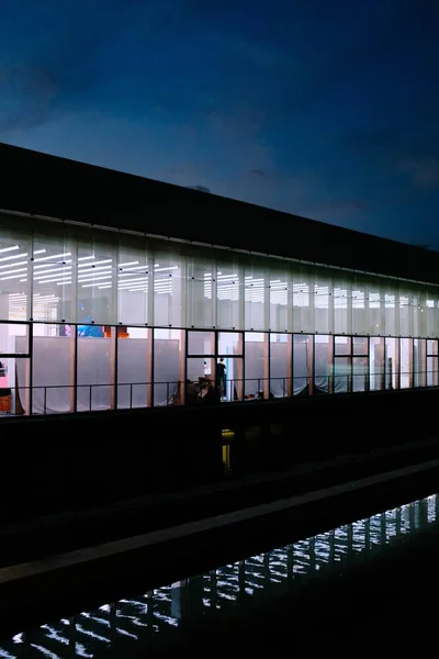 Geceleri çekilen cam modern bir binanın dikey görüntüsü. — Stok fotoğraf