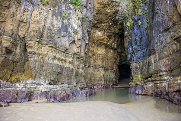 Τοπίο σπηλαίου με ψηλούς πέτρινους τοίχους καλυμμένους με πράσινο που περιβάλλεται από νερό — Φωτογραφία Αρχείου