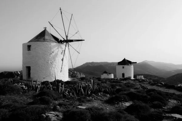 Plan en échelle grise de moulins à vent au milieu d'un champ entouré d'un paysage montagneux — Photo