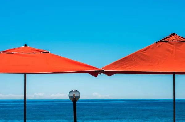 Strandresort met twee rode parasols met een reflecterende kristallen bol in het midden — Stockfoto