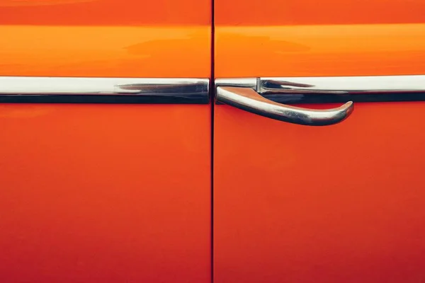 Primo piano della maniglia della porta in metallo di un'auto arancione — Foto Stock