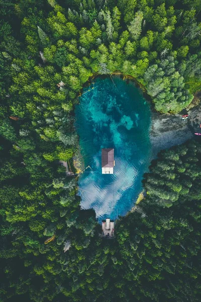 Vista de alto ângulo de um edifício em um lago cercado por florestas sob um céu nublado — Fotografia de Stock