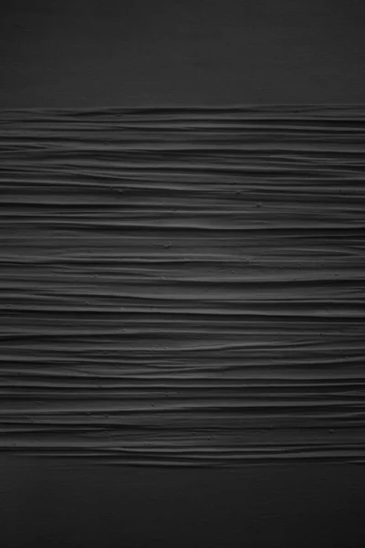 Balança de cinza vertical dos padrões em uma parede pintada de preto — Fotografia de Stock