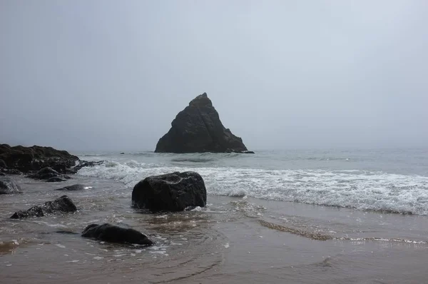 Paisaje del mar desde la orilla rodeado de rocas bajo un cielo gris — Foto de Stock