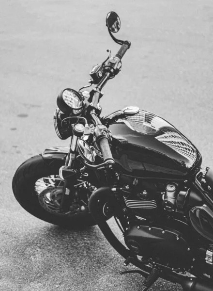 Vertikale Graustufenaufnahme eines schönen schwarzen Motorrads am Straßenrand — Stockfoto