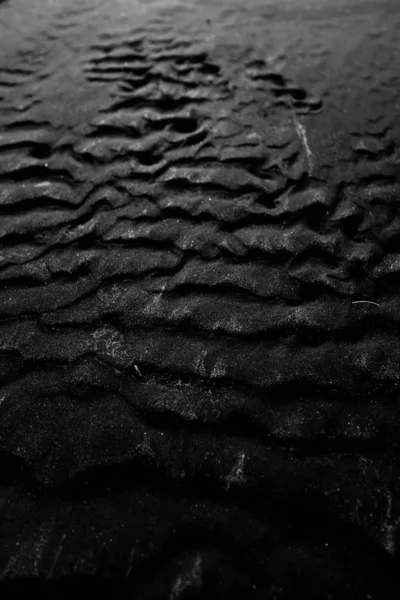 Kühler Graustufenhintergrund aus feuchtem schwarzem Sand - ideal für Hintergrund oder Tapete — Stockfoto