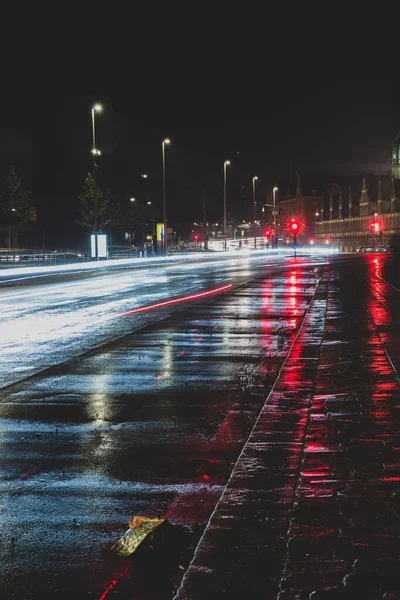 Vertikal bild av reflektioner av röda gatlyktor på marken av den våta motorvägen på natten — Stockfoto