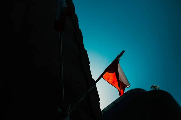 Silueta de un edificio alto y una bandera capturada al atardecer — Foto de Stock