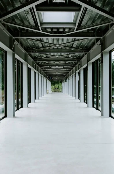 Imagen vertical de un pasillo blanco con puertas de cristal y techo de metal en un edificio moderno —  Fotos de Stock