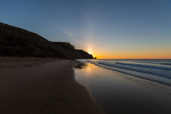 Paisagem do mar rodeada de rochas sob um céu azul e reflexo do pôr do sol em Portugal — Fotografia de Stock