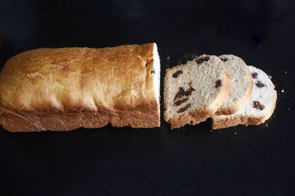 High angle picture of a white cut pastry with raisins on a black table — Stock Photo, Image