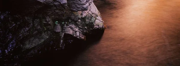 Vue en angle élevé d'un gros rocher dans la rivière Washington State sous la lumière du soleil pendant le coucher du soleil — Photo
