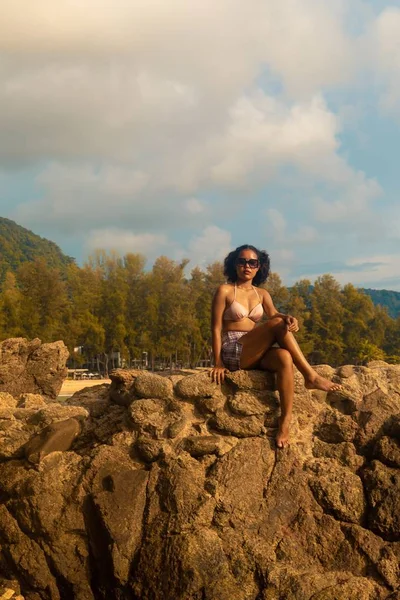 Pionowe Ujęcie Samicy Siedzącej Skale Cieszącej Się Pięknym Dniem Plaży — Zdjęcie stockowe
