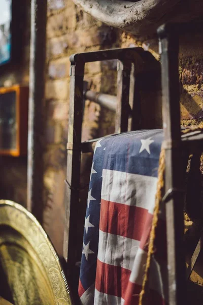 A vertical shot of the flag of the United States hung on a metal stand in an ancient attic