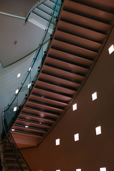 Low angle shot of a brown handrail in a building with square lamps in the walls — Stock Photo, Image