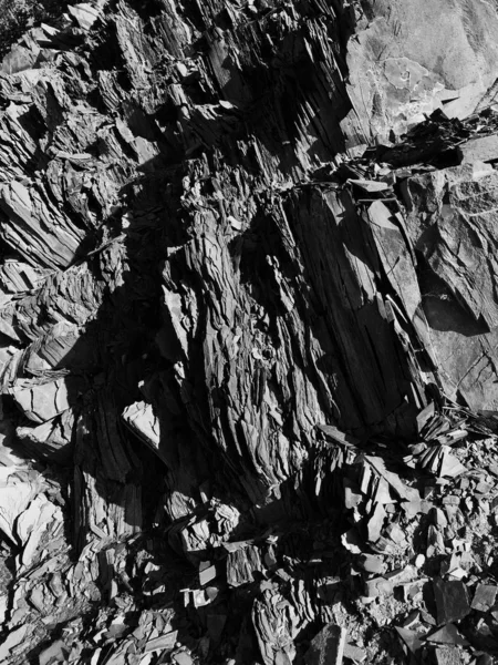 Vertikale Graustufenaufnahme der Schichten alter schöner Felsen auf einem Berg — Stockfoto