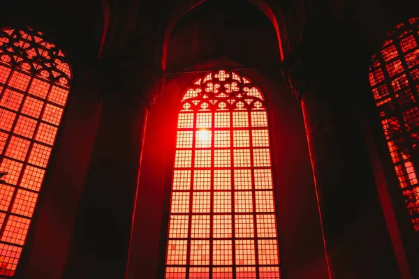 Baixo ângulo tiro da luz vermelha do sol brilhando através das janelas em forma de arco em um edifício antigo — Fotografia de Stock