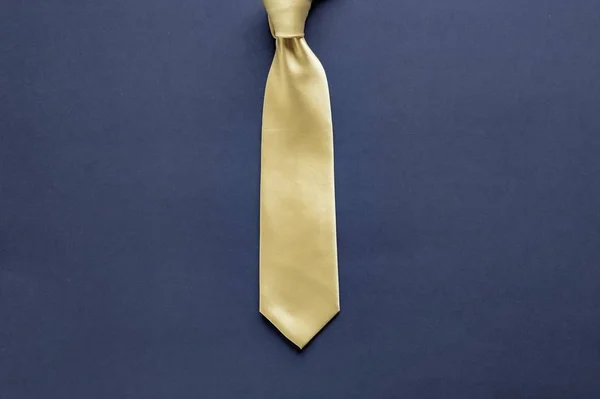 Gravata amarela em uma superfície azul escura — Fotografia de Stock