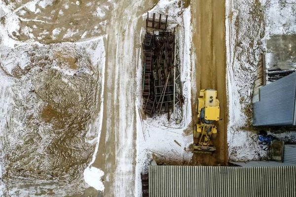 Vista de alto ângulo de um caminhão amarelo em uma sujeira cercada por edifícios e grama coberta de neve — Fotografia de Stock