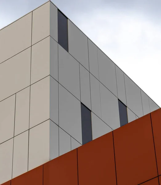 Tiro de ângulo baixo de um moderno edifício branco e laranja sob o céu brilhante — Fotografia de Stock