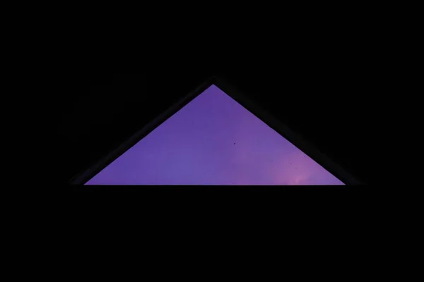 Closeup shot of a perfect triangle window looking at the mesmerizing purple sky — ストック写真