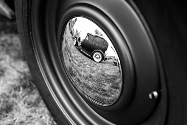 Başka bir arabanın tekerleğindeki klasik arabanın yansımasının gri ölçekli görüntüsü. — Stok fotoğraf