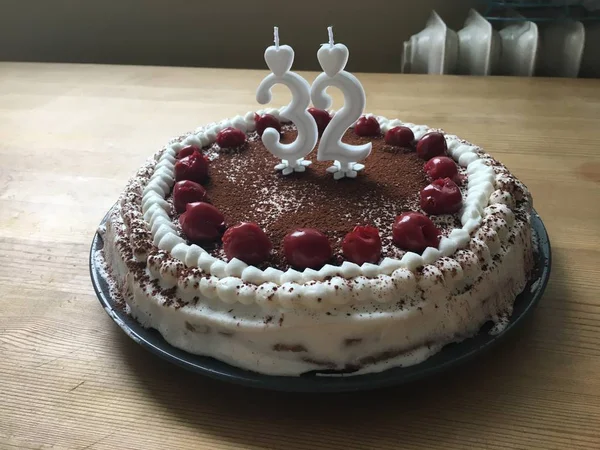 Urodzinowy tort czekoladowy z jagodami i białymi dodatkami i świecami na drewnianym stole — Zdjęcie stockowe