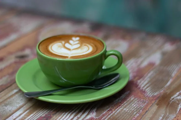 Zbliżenie cappuccino z malowidłami w kształcie serca na pianie w zielonej filiżance — Zdjęcie stockowe