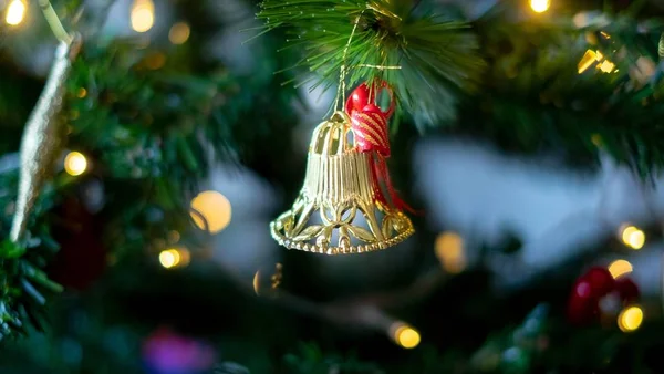 Closeup de um sino de brinquedo de árvore de Natal cercado por decorações e luzes com um efeito bokeh — Fotografia de Stock