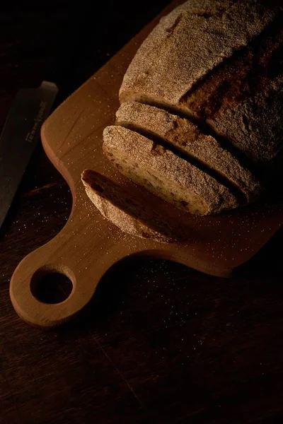 Tiro de ângulo alto de pão fatiado em uma tábua de corte em uma superfície de madeira — Fotografia de Stock
