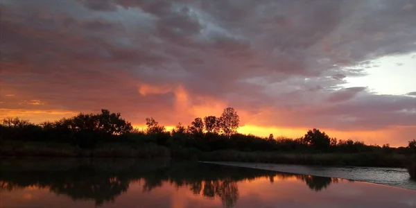 Vacker grumlig solnedgång över en sjö på landet — Stockfoto