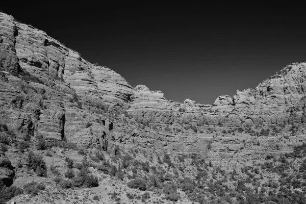 Paesaggio in scala di grigi di rocce ricoperte di foreste e polvere sotto un cielo — Foto Stock